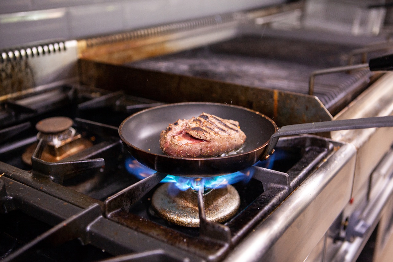 Steak searing in a pan over open flame